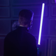 A man holding a lightsaber in a training pod to fight off beams.